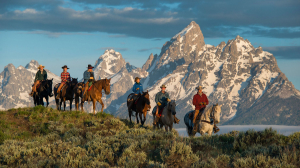Group of people on horses with mountains in the background