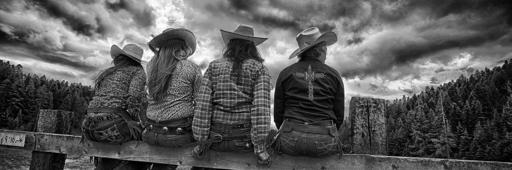 Four cowgirls sitting on a fence