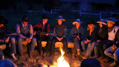 Guests playing music around a camp fire at CM Ranch