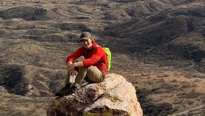 Teen guest sitting on a rock at the end of a hike at Circle Z Ranch