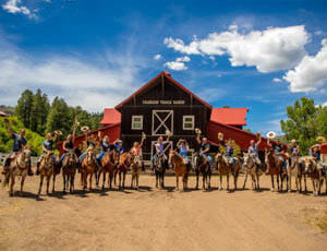 Family group on horses outside of a barn at Colorado Trails Ranch