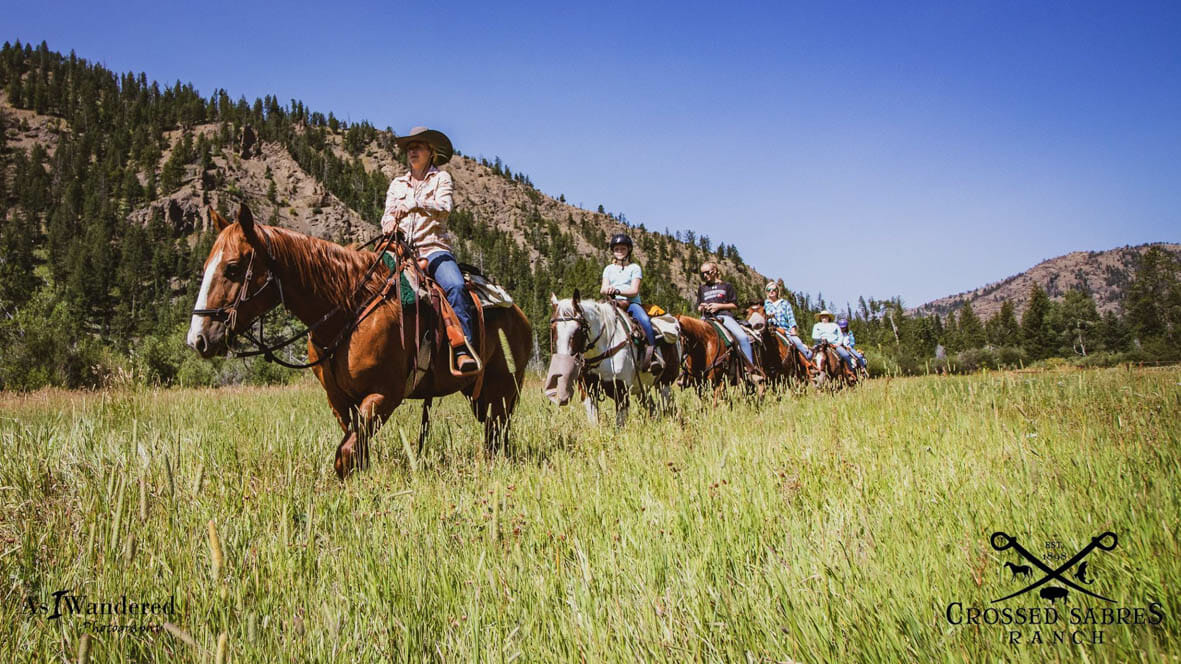 Trail ride through green field at Crossed Sabres Ranch