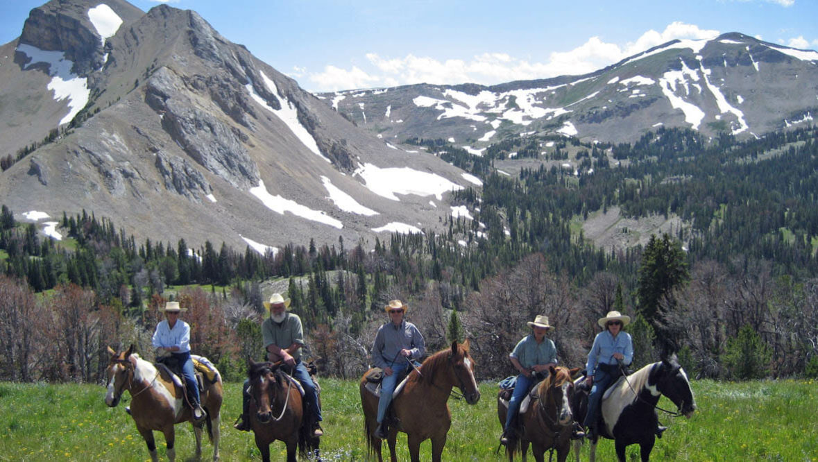Guests on horses in a line in front of mountains at Elkhorn Ranch Montana