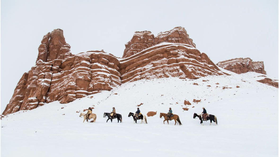 Trail ride in the snow by red rocks at Hideout Lodge Ranch
