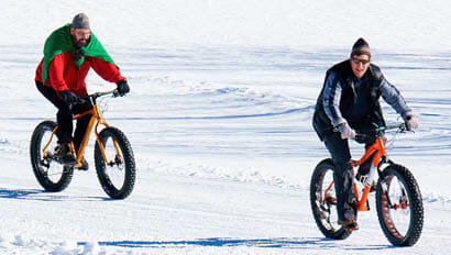 Two guests riding fat tire bikes on snow at Latigo Dude Ranch