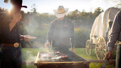 Cowboy grilling food outside at Lost Valley Ranch