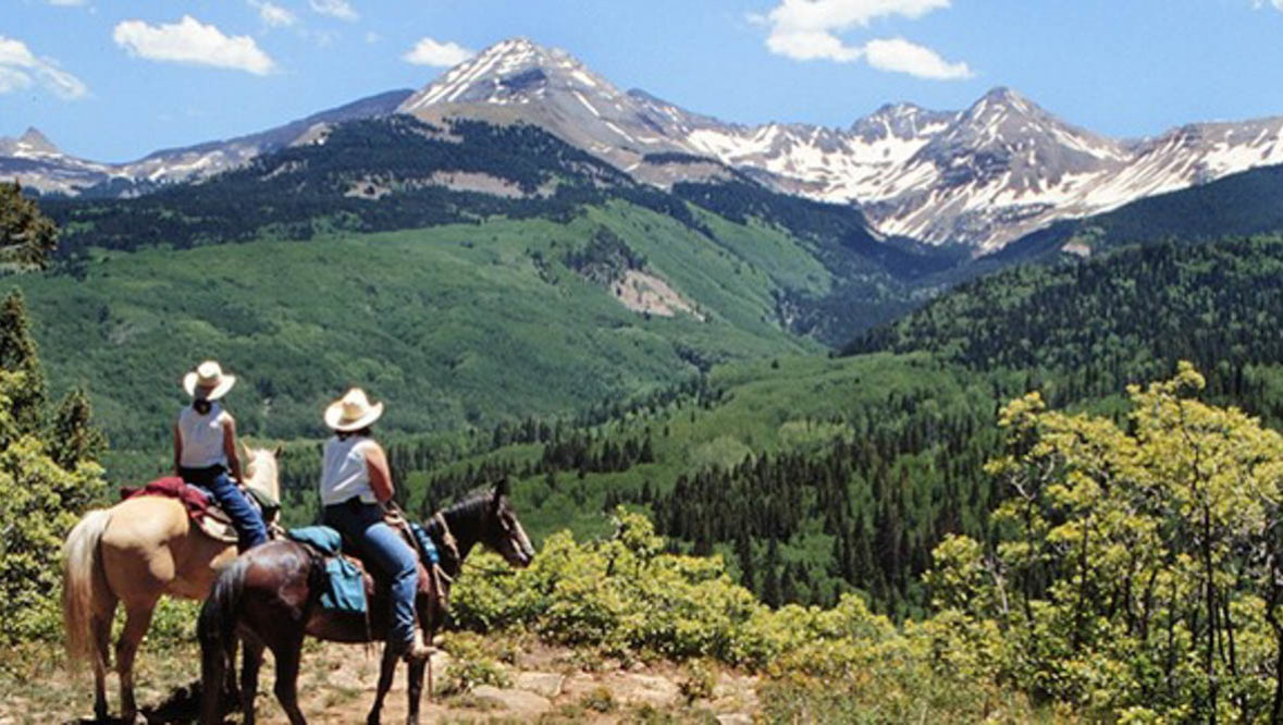 Guests on horses looking out at the beautiful mountain view at Majestic Dude Ranch