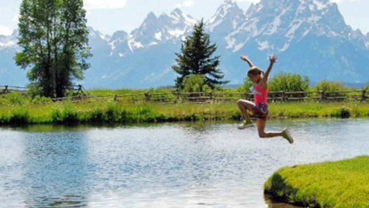 Kid jumping into a river at Moosehead Ranch