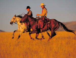 Two riders on a trail loping at Paradise Guest Ranch