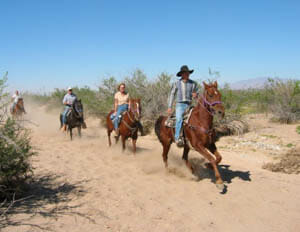 People galloping on a trail at Stagecoach Trail Guest Ranch