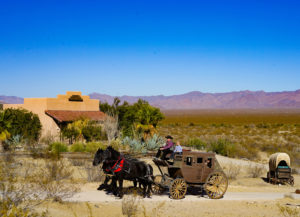 Stagecoach wagon being pulled by two horses with Mountains in background