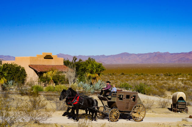 Stagecoach wagon being pulled by two horses with Mountains in background