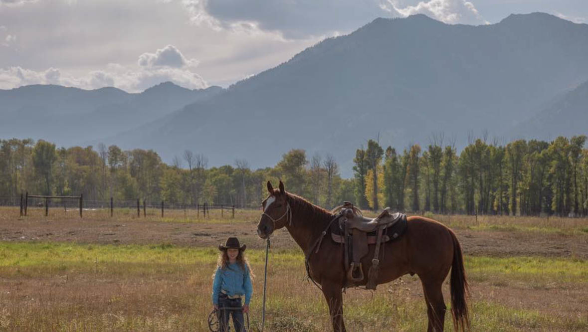 Little girl standing next to a horse at Triangle C Ranch