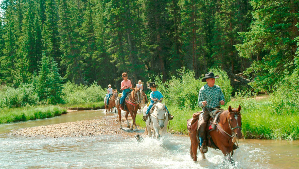 Tumbling River horses and riders crossing a creek