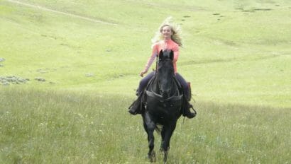 young cowgirl galloping in a field