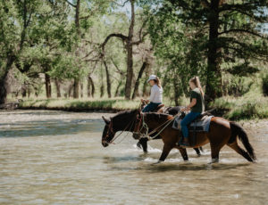 Two riders crossing creek on horses