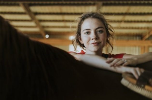 Girl with arms crossed on horses back
