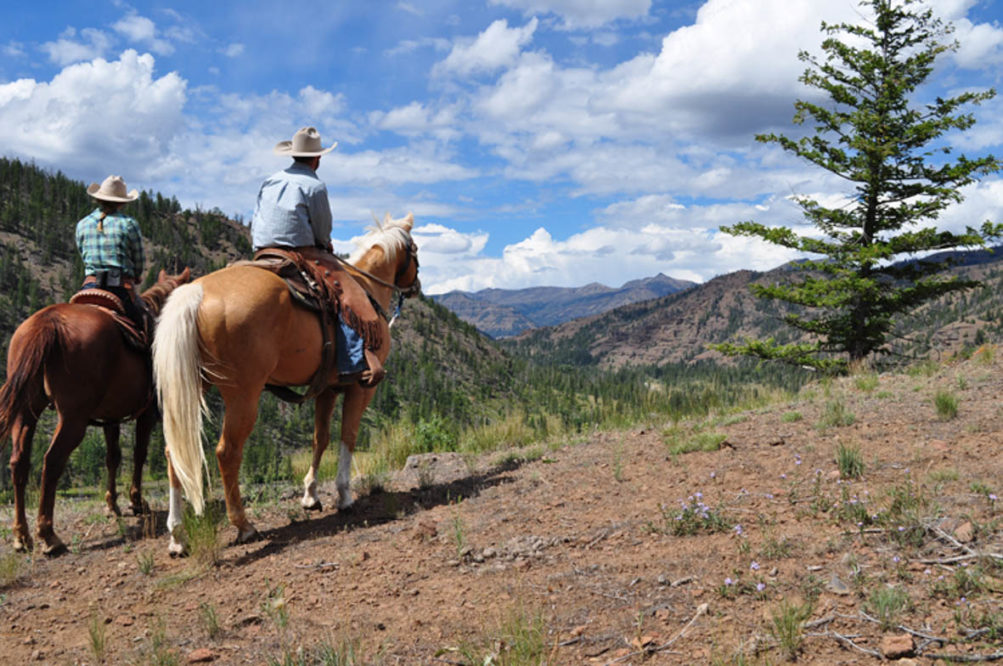 Two guests on horses looking out at the view at Crossed Sabres Ranch