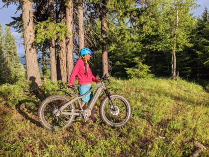 Lady with ebike in the mountains with green trees