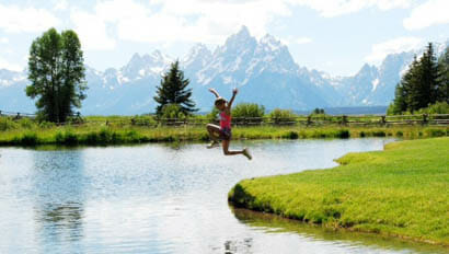 Kid jumping into a river at Moosehead Ranch