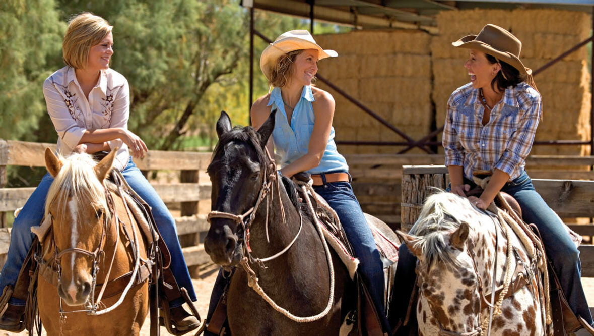 Three cowgirls riding horses at Rancho de los Caballeros