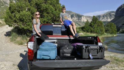 Kids on the back of a pickup truck filled with luggage