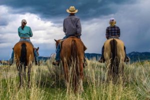3 people lined up on horses